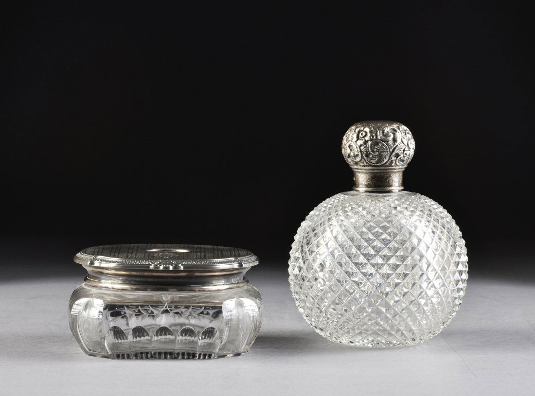 TWO STERLING MOUNTED CUT CRYSTAL GLASS DRESSING TABLE A: TWO STERLING MOUNTED CUT CRYSTAL GLASS DRESSING TABLE ACCESSORIES, AMERICAN AND ENGLISH, EARLY 20TH CENTURY, the American bombé rectangular hair receptacle with sides centering a cut stylized scrolli