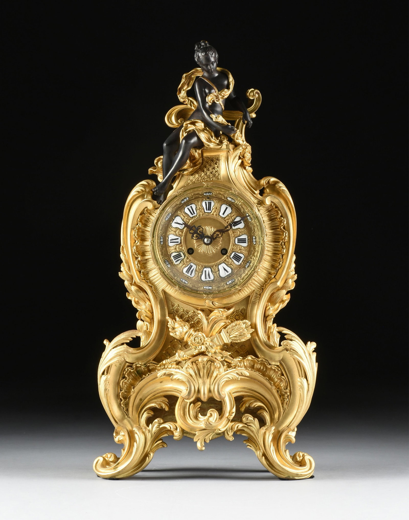 A ROCOCO STYLE MANTLE CLOCK, FRENCH, CIRCA 1890,: A ROCOCO STYLE MANTLE CLOCK, FRENCH, CIRCA 1890, a gilt bronze clock topped with a patinated bronze nude figure of a woman, with enamel roman and arabic numerals on face. 22 x 11 x 6 in. (55.9 x 27.9 