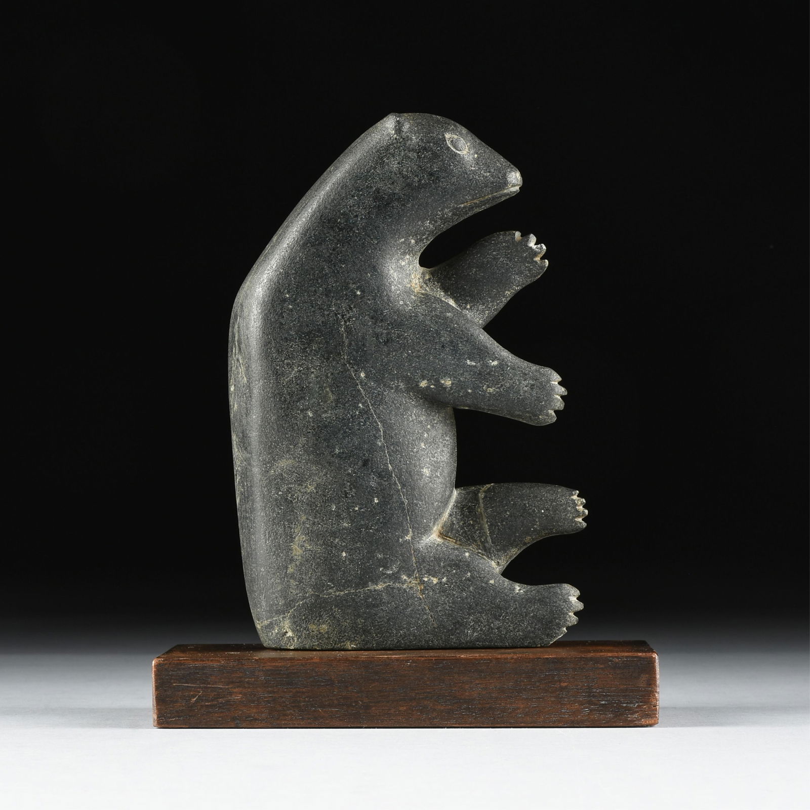 JOHNNIEBO ASKEVAK (Inuit 1923- 1972) "Bear," 1960s: JOHNNIEBO ASKEVAK (Inuit 1923- 1972) "Bear," 1960sa carved soapstone sculpture of a bear mounted on a wooden base.9 1/4 x 5 3/4 x 2 in. (23.5 x 14.6 x 5.1 cm.) Provenance: Property of a National Insur