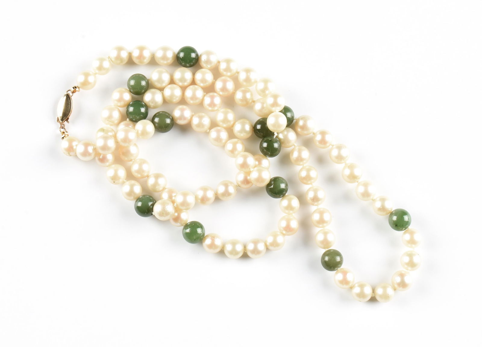 A PEARL AND JADE NECKLACE,: A PEARL AND JADE NECKLACE,seventy-six cultured pearls (approximately 7mm each) and twelve round jade beads strung cream-colored knotted silk, with a 14 karat gold fish hook clasp. Total approximate we