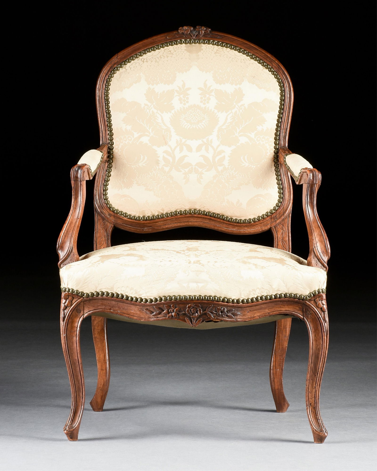 A ROCOCO STYLE WALNUT ARMCHAIR, FRENCH, 19TH/20TH CENTURY,: A ROCOCO STYLE WALNUT ARMCHAIR, FRENCH, 19TH/20TH CENTURY,a carved walnut armchair with silk upholstery.36 x 24 x 23 in. (91.4 x 61 x 58.4 cm.)Provenance: Collection of the Norbert Choucroun Trust, Ho