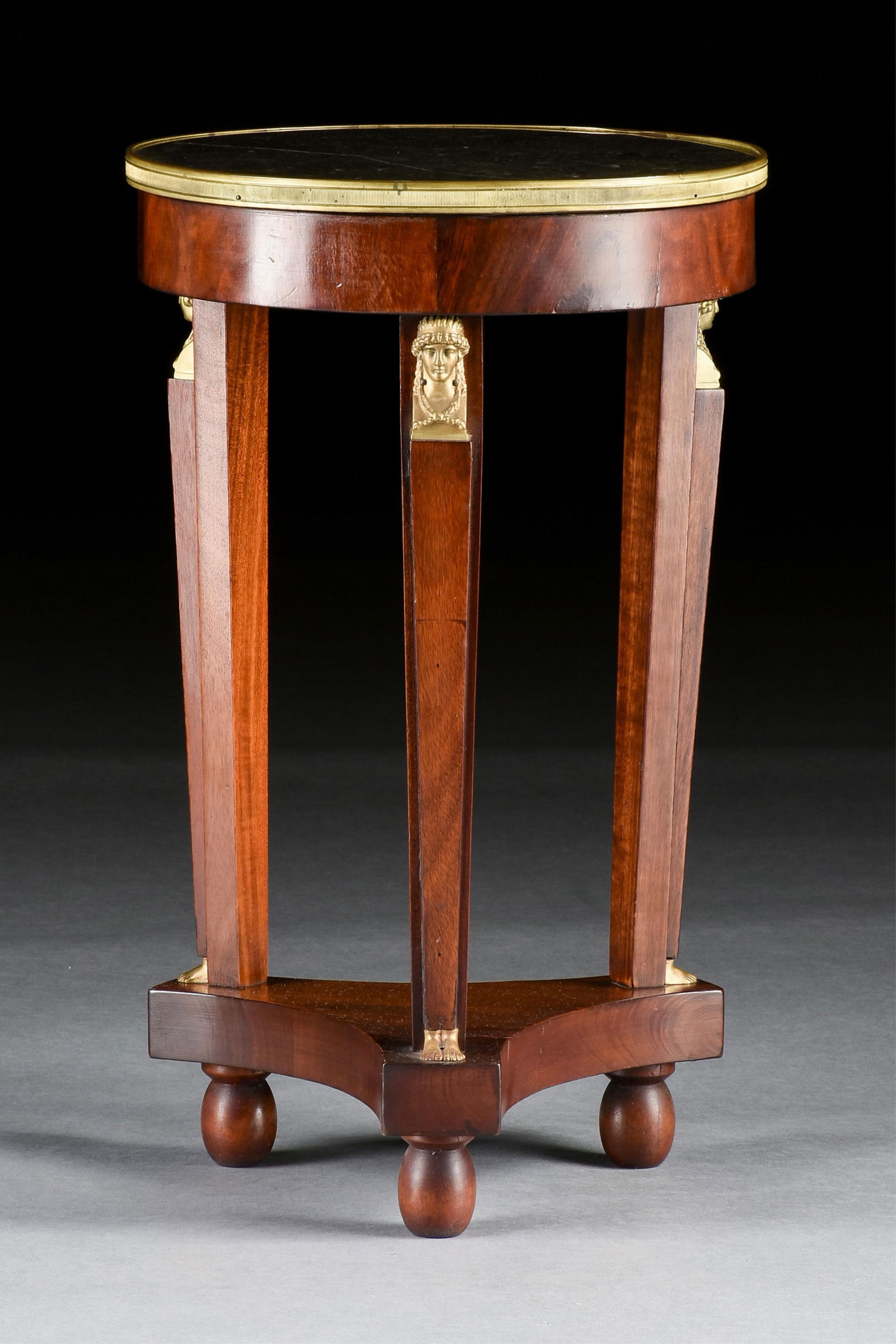 A NEOCLASSICAL STYLE BRONZE ORMOLU-MOUNTED MAHOGANY GUERIDON, FRENCH, 19TH/20TH CENTURY,: A NEOCLASSICAL STYLE BRONZE ORMOLU-MOUNTED MAHOGANY GUERIDON, FRENCH, 19TH/20TH CENTURY,a round mahogany table with three supports ornamented with gilt bronze caryatid figures and topped with fossil m