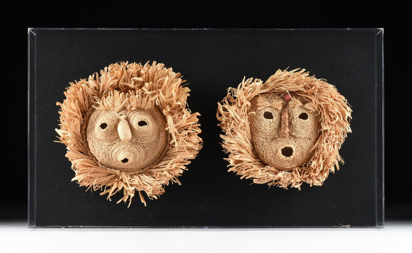 TWO CORN HUSK MASKS, IROQUOIS, 20TH CENTURY,: TWO CORN HUSK MASKS, IROQUOIS, 20TH CENTURY,two masks made from corn husks and mounted in a custom display case.Case: 19 3/8 x 34 3/8 x 7 3/8 in. (49.2 x 87.3 x 18.7 cm.) Provenance: Property of a Nat