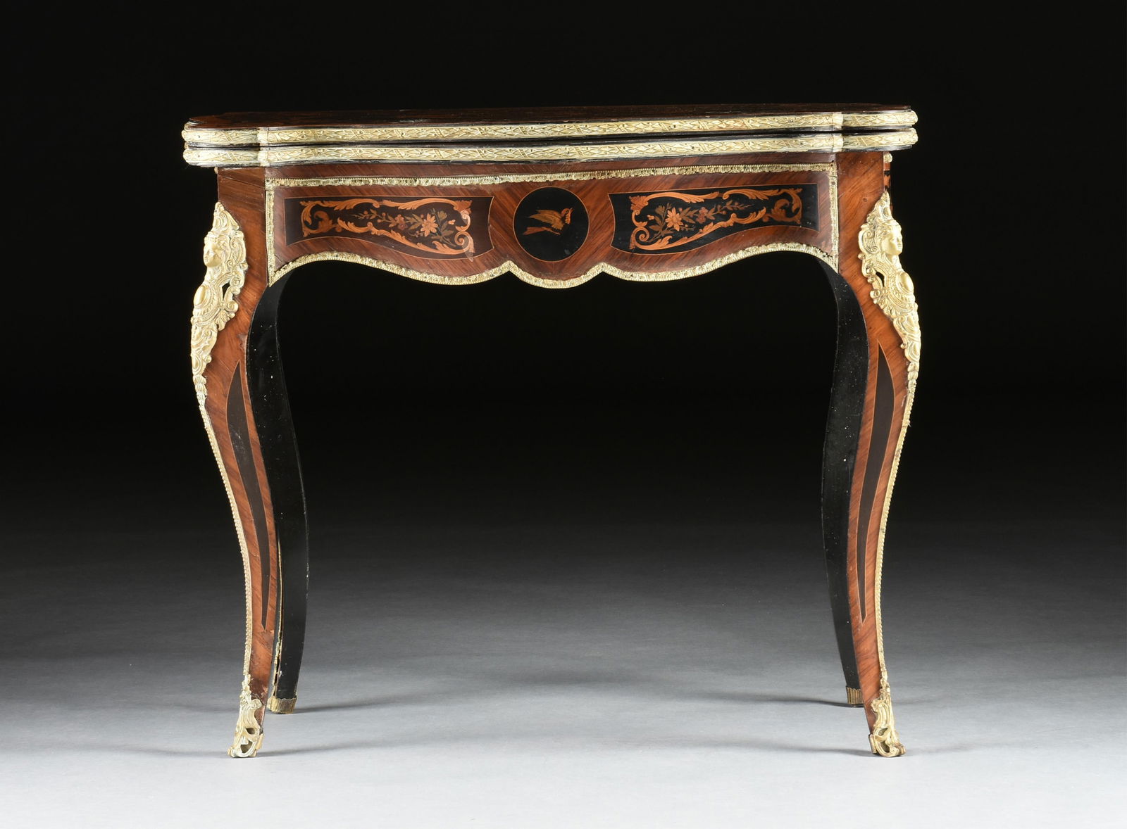 A NAPOLEON III MARQUETRY CARD TABLE, FRENCH, LATE 19TH CENTURY,: A NAPOLEON III MARQUETRY CARD TABLE, FRENCH, LATE 19TH CENTURY,an ebonized and veneered folding card table with various inlaid woods and bronze mounts that opens to reveal a card table lined with gree