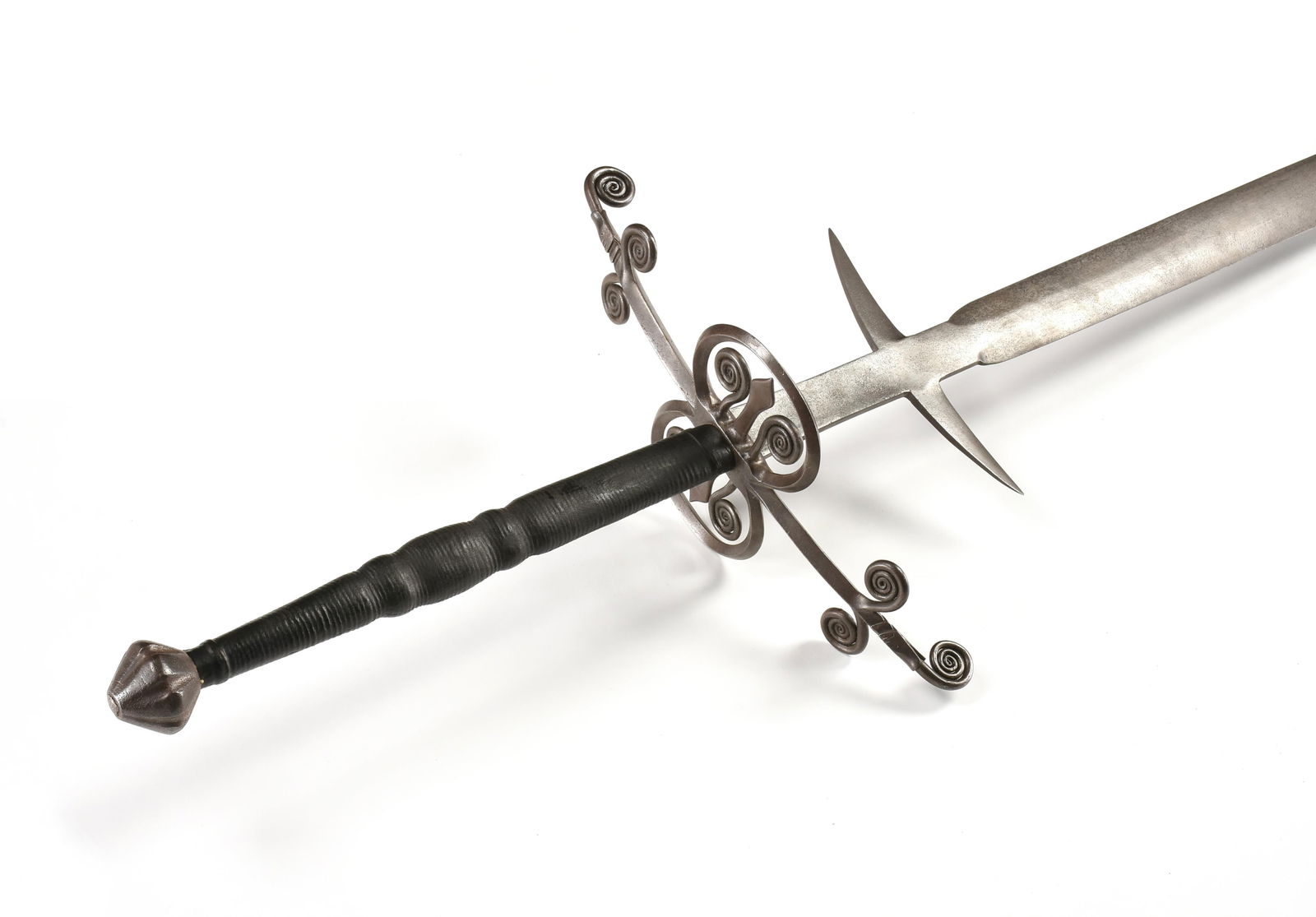 A TWO-HANDED SWORD, GERMAN, 16TH CENTURY,: A TWO-HANDED SWORD, GERMAN, 16TH CENTURY,a double edged blade with a long ricasso with parrying hooks and a guard with serpent headed quillons with coiled tongues, fleur-de-lys side rings, a biconical