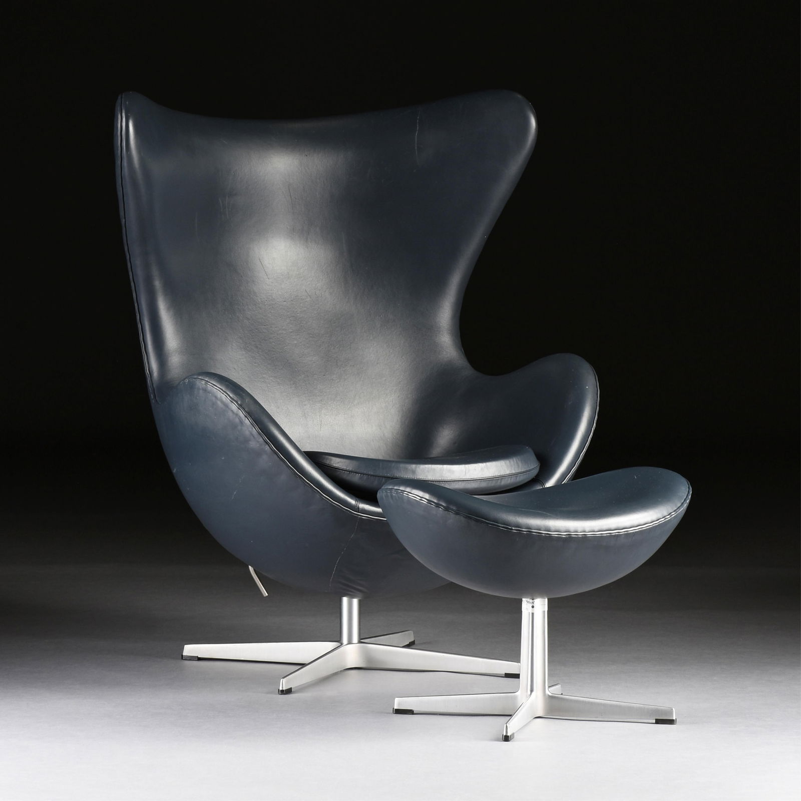 ARNE JACOBSEN (Danish 1902-1971) A FRITZ HANSEN EGG CHAIR AND OTTOMAN, DANISH, 2000,: ARNE JACOBSEN (Danish 1902-1971) A FRITZ HANSEN EGG CHAIR AND OTTOMAN, DANISH, 2000,a mid-century modern chair and ottoman with metal bases and leather upholstery, with Fritz Hansen labels on the base