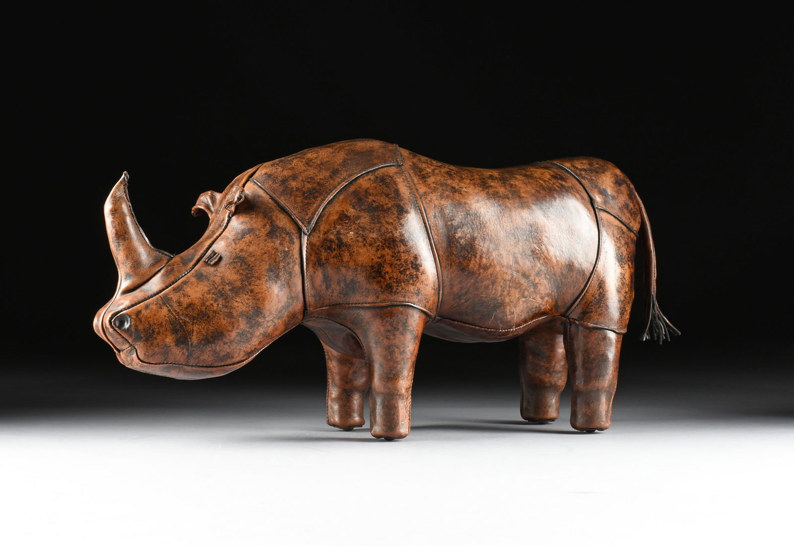DIMITRI OMERSA FOR ABERCROMBIE & FITCH, A RHINOCEROS FOOTSTOOL, ENGLISH, CIRCA 1960s.: DIMITRI OMERSA FOR ABERCROMBIE & FITCH, A RHINOCEROS FOOTSTOOL, ENGLISH, CIRCA 1960s.a leather upholstered footstool.17 1/2 x 36 x 10 in. (44.5 x 91.4 x 25.4 cm.)