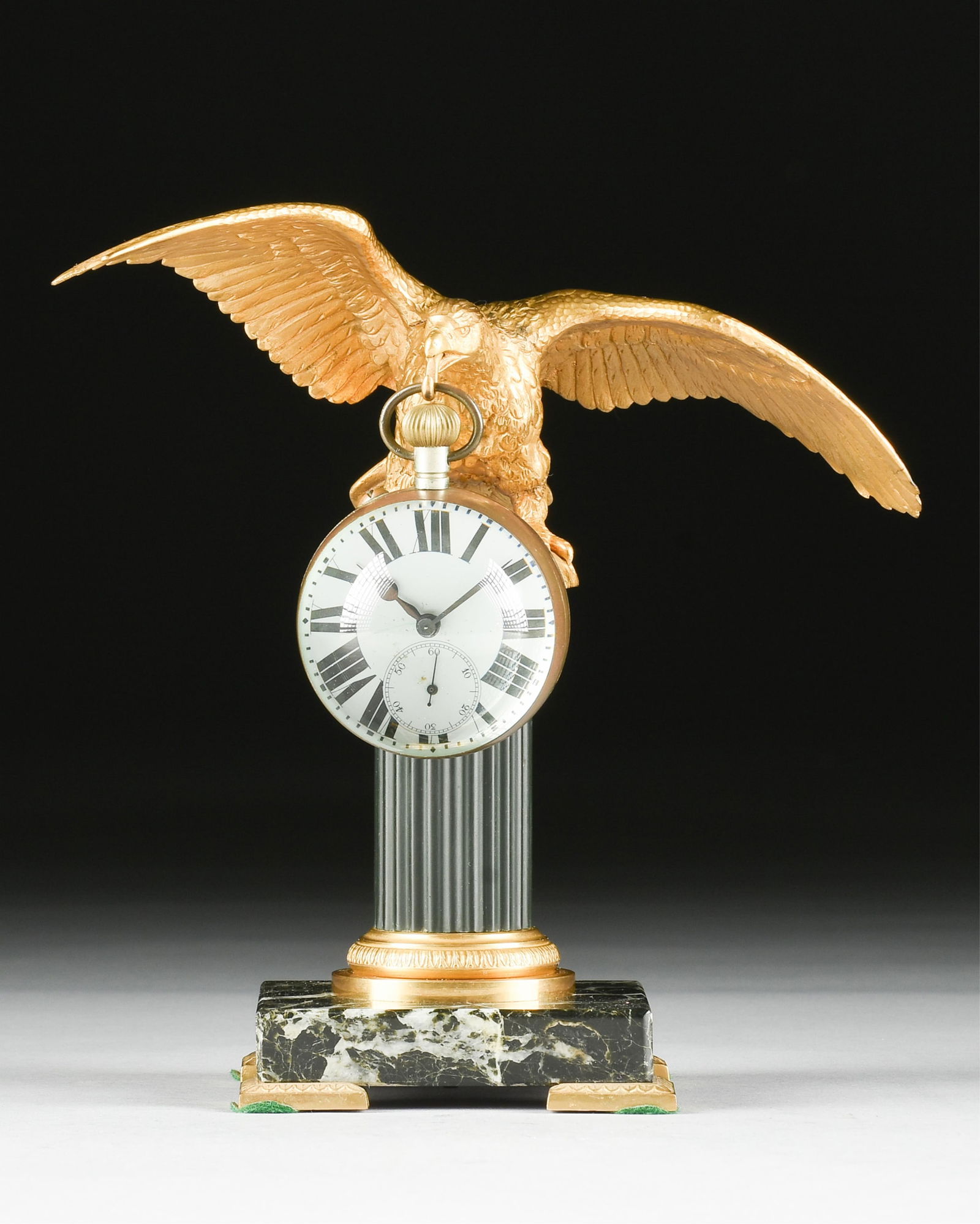 AN EMPIRE STYLE BRONZE ORMOLU POCKET WATCH HOLDER AND CLOCK, FRENCH, 19TH/20TH CENTURY,: AN EMPIRE STYLE BRONZE ORMOLU POCKET WATCH HOLDER AND CLOCK, FRENCH, 19TH/20TH CENTURY,gilt bronze eagle with a hook extending from its beak to hold a pocket watch, perched atop a fluted column on a m