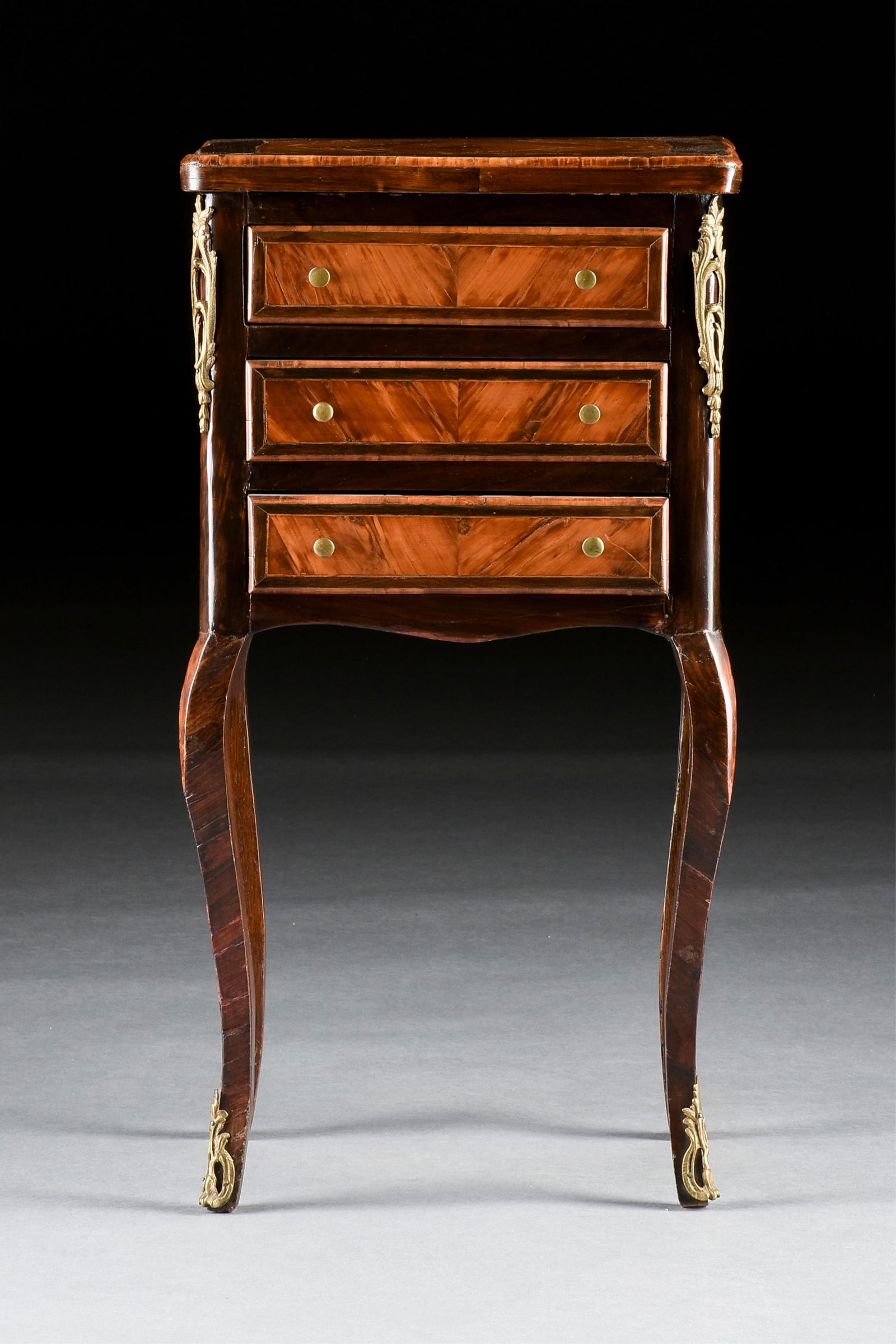 A ROCOCO STYLE NIGHT STAND, FRENCH, 19TH/20TH CENTURY,: A ROCOCO STYLE NIGHT STAND, FRENCH, 19TH/20TH CENTURY,a three drawer bedside table with oak, fruit wood, and gilt bronze mounts.29 1/2 x 16 x 12 in. (74.9 x 40.6 x 30.5 cm.) Provenance: Collection of