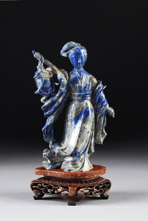 A CHINESE CARVED LAPIS FIGURE OF GUANYIN ON STAND, 20TH: A CHINESE CARVED LAPIS FIGURE OF GUANYIN ON STAND, 20TH CENTURY, standing with flowing robes and holding a lantern in one hand. Height: 5 5/8" Width: 3 1/2" Depth: 1 1/4"