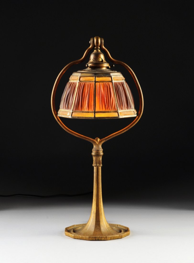 A TIFFANY 'FABRIQUE' FAVRILE GLASS AND BRONZE LAMP, EAR: A TIFFANY 'FABRIQUE' FAVRILE GLASS AND BRONZE LAMP, EARLY 20TH CENTURY, the shade stamped "TIFFANY STUDIOS NEW YORK 1938," the base stamped "TIFFANY STUDIOS | NEW YORK | 613," the decagonal shade inse