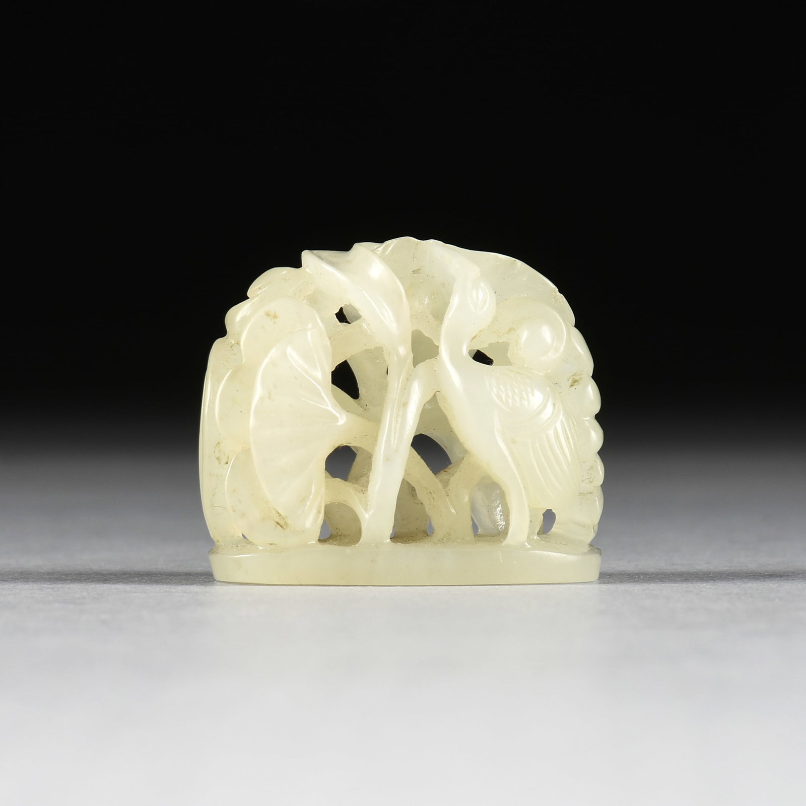 A CELADON JADE COURT HAT FINIAL, CHINESE, POSSIBLY YUAN/MING DYNASTY, 1271-1644,: A CELADON JADE COURT HAT FINIAL, CHINESE, POSSIBLY YUAN/MING DYNASTY, 1271-1644, carved pale celadon jade finial portraying cranes and lotus, with four small holes on base for mounting to a hat.