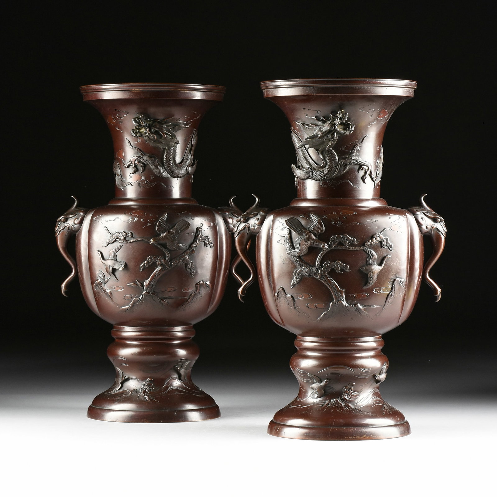 A LARGE PAIR OF BRONZE URNS, CHINESE OR JAPANESE, 19TH/20TH CENTURY,: A LARGE PAIR OF BRONZE URNS, CHINESE OR JAPANESE, 19TH/20TH CENTURY, two patinated bronze urns with elephant head handles and ornamented with dragons and birds. Each: 24 1/4 x 14 1/2 x 11 in. (61.6 x