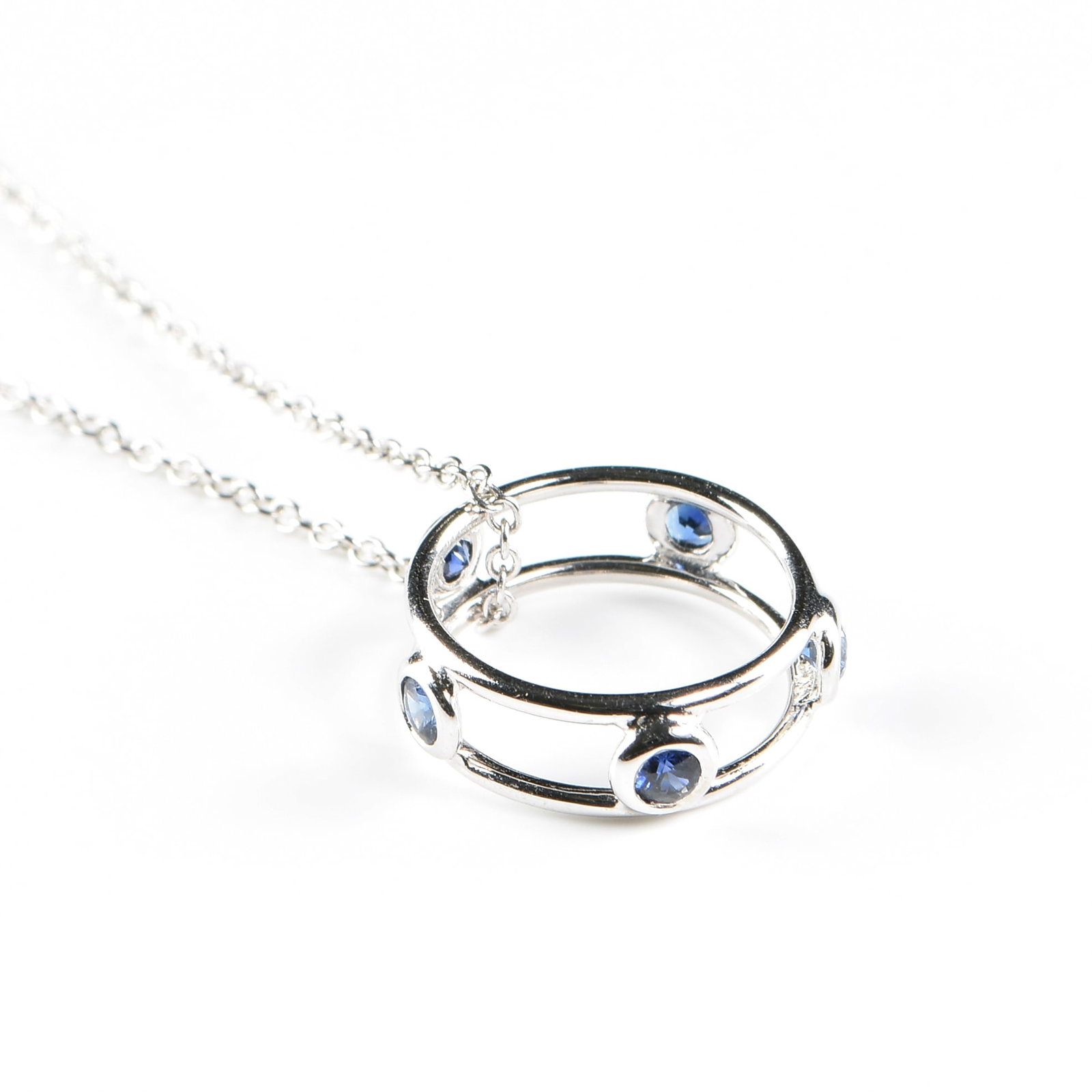 ELSA PERETTI (Italian 1940-2021) A TIFFANY & CO. 18K GOLD Color by the Yard SAPPHIRE PENDANT: ELSA PERETTI (Italian 1940-2021) A TIFFANY & CO. 18K GOLD Color by the Yard SAPPHIRE PENDANT NECKLACE, 18k white gold pendant necklace with a double ring pendant set with five round faceted blue sapph