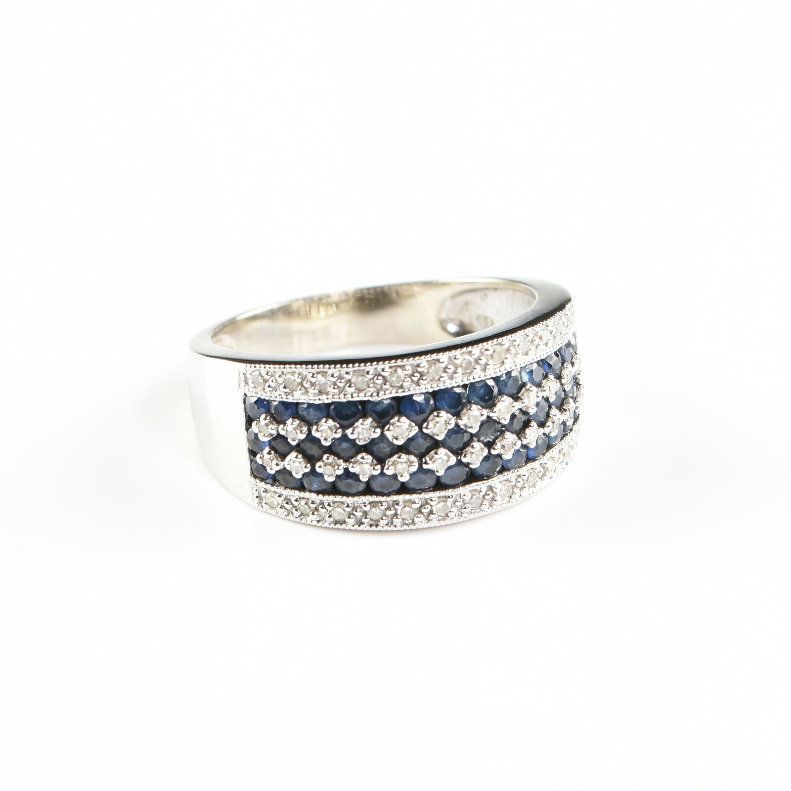 A SYDNEY BERMAN 14K GOLD, DIAMOND, AND SAPPHIRE RING, AMERICAN, CIRCA 1950,: A SYDNEY BERMAN 14K GOLD, DIAMOND, AND SAPPHIRE RING, AMERICAN, CIRCA 1950, 14k white gold band with five alternating rows of round faceted dark royal blue sapphires (approx. 1.7 mm each) and bead set