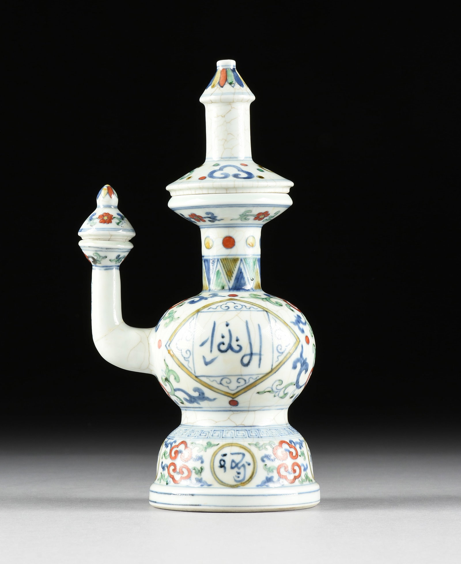 A ZHENGDE PERIOD DOUCAI EWER, CHINESE, MING DYNASTY, 1505-1521,: A ZHENGDE PERIOD DOUCAI EWER, CHINESE, MING DYNASTY, 1505-1521, porcelain vessel of Tibetan form with blue underglaze with green, red, and yellow enamel overglaze, and with Arabic script on the sides,