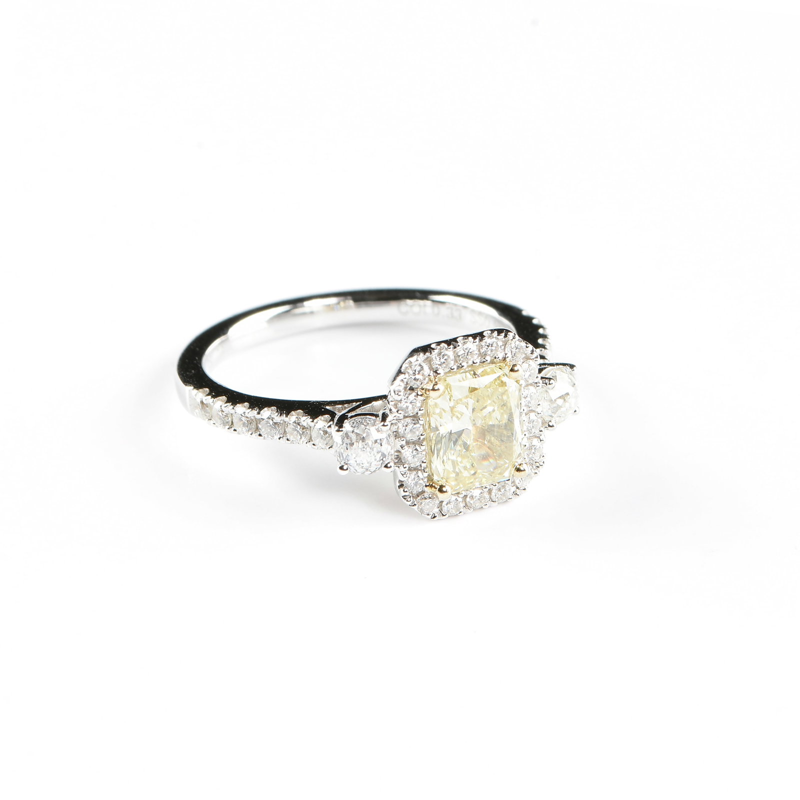 A 14K GOLD AND FANCY YELLOW DIAMOND HALO RING,: A 14K GOLD AND FANCY YELLOW DIAMOND HALO RING, 14k white gold ring set with a 1.08 carat radiant cut fancy yellow diamond surrounded by a halo of round brilliant cut diamonds, flanked by two crown of 