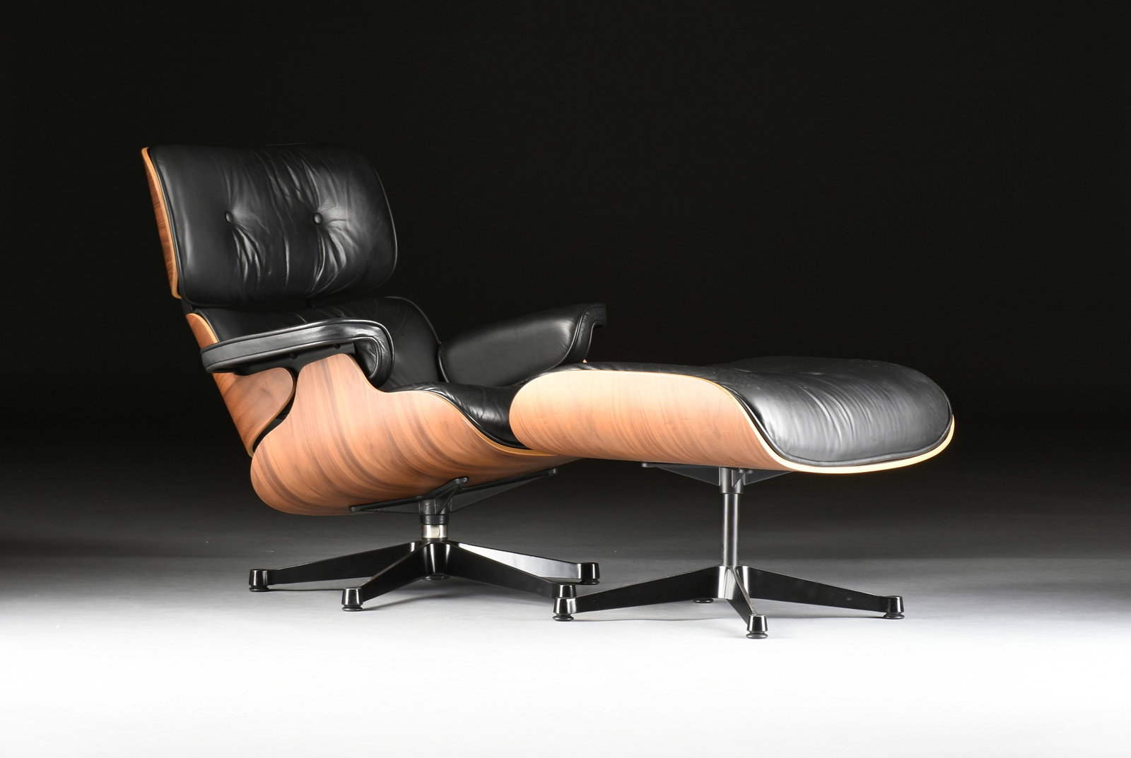 A MID-CENTURY MODERN STYLE LOUNGE CHAIR AND OTTOMAN, 21ST CENTURY,: A MID-CENTURY MODERN STYLE LOUNGE CHAIR AND OTTOMAN, 21ST CENTURY, molded plywood and tufted leather upholstery on an aluminum base in the style of Charles and Ray Eames. Chair: 31 1/2 x 32 x 32 in. (