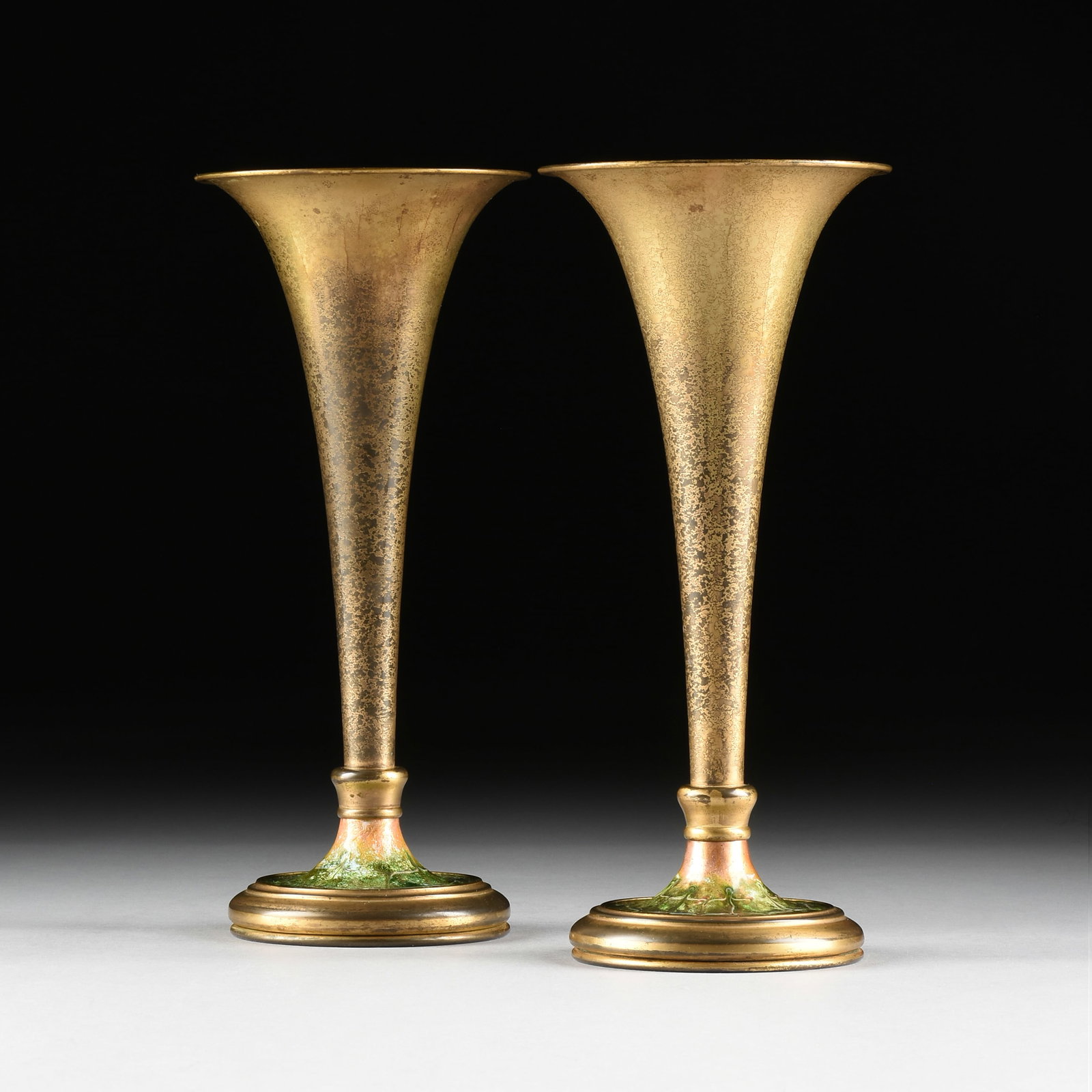 A PAIR OF LOUIS C. TIFFANY FURNACES GILT AND ENAMELLED BRONZE TRUMPET VASES, AMERICAN, CIRCA 1920,: A PAIR OF LOUIS C. TIFFANY FURNACES GILT AND ENAMELLED BRONZE TRUMPET VASES, AMERICAN, CIRCA 1920, two parcel gilt and acid etched bronze vases with green enamelled bases, marked on each base, "Louis