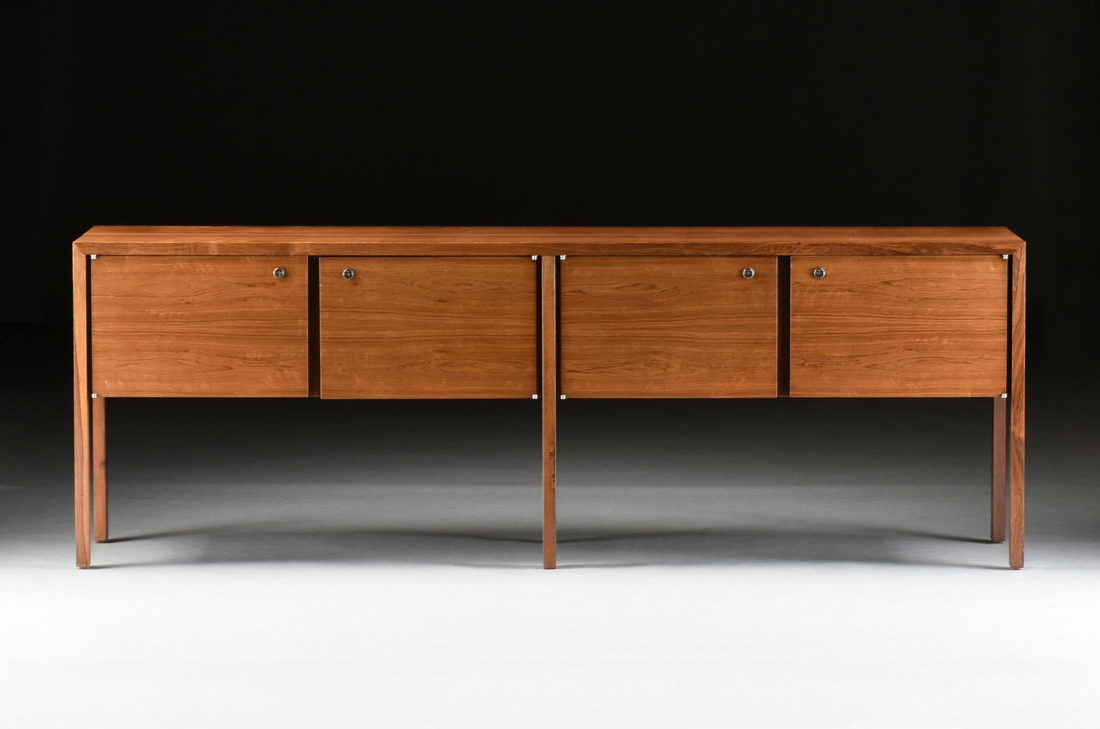 A HARVEY PROBBER CREDENZA, AMERICAN, CIRCA 1970,: A HARVEY PROBBER CREDENZA, AMERICAN, CIRCA 1970, mid-century modern walnut credenza with four locking cabinets, two of which contain an adjustable leather-covered shelf. 28 3/4 x 82 3/4 x 18 in. (73 x