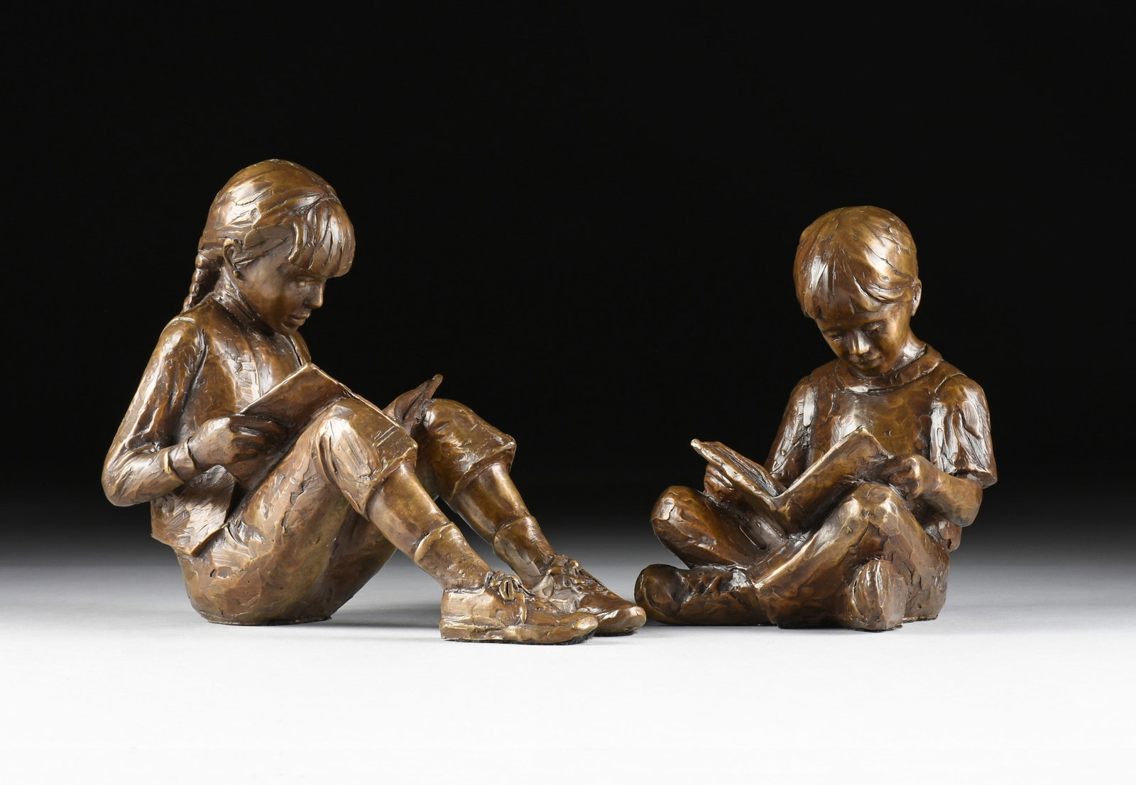 GARY PRICE (American b. 1955) Storytime: Boy and Girl Reading, 1992,: GARY PRICE (American b. 1955) Storytime: Boy and Girl Reading, 1992, pair of patinated bronze sculptures of children sitting down and reading books, each signed and dated on book pages, "G. Price 