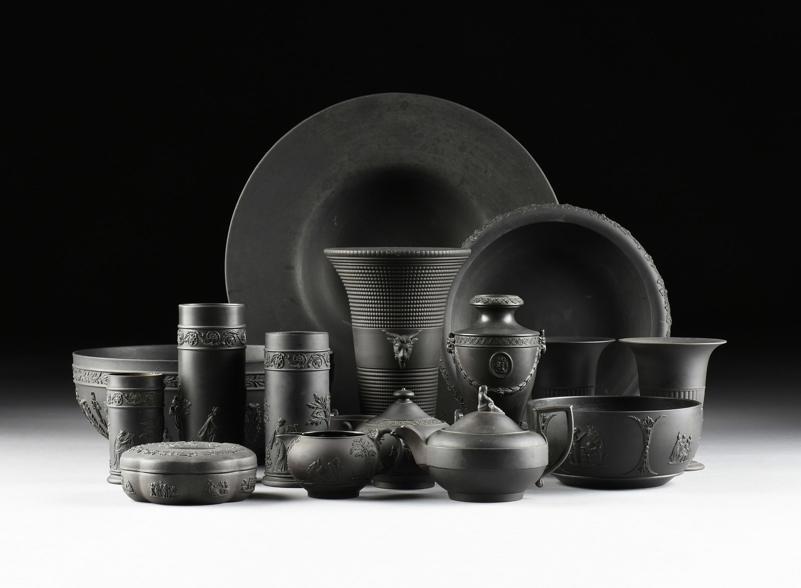 A SIXTEEN-PIECE WEDGWOOD HOLLOWARE SET, BRITISH, 19TH/20TH CENTURY,: A SIXTEEN-PIECE WEDGWOOD HOLLOWARE SET, BRITISH, 19TH/20TH CENTURY, black basalt stoneware, all marked on underside, "Wedgwood," and most with date marks, including a large rimmed centerpiece bowl (18