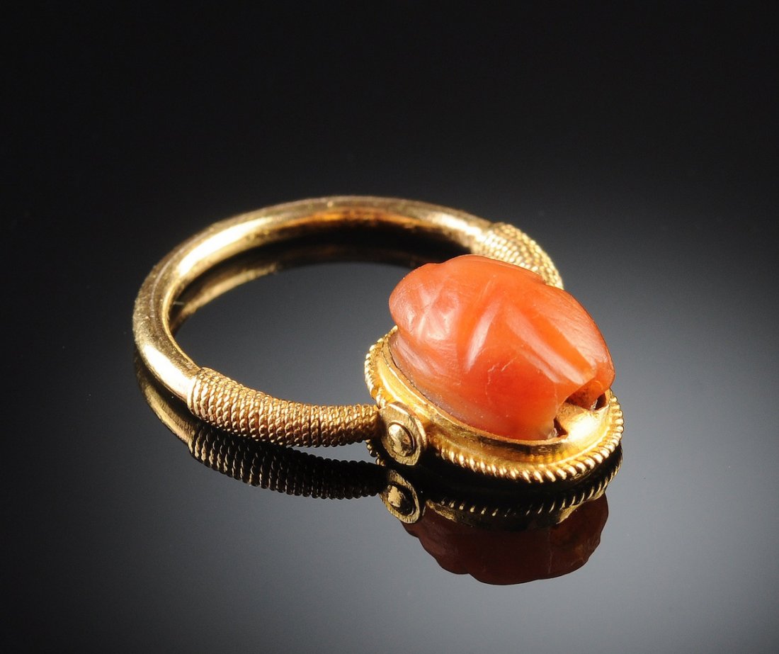 AN EGYPTIAN REVIVAL CARNELIAN SCARAB RING, PROBABLY LAT: AN EGYPTIAN REVIVAL CARNELIAN SCARAB RING, PROBABLY LATE 19TH CENTURY, the reversible carved scarab mounted on an 18K yellow gold swivel setting. Length of scarab: 6 mm. Provenance: private collection