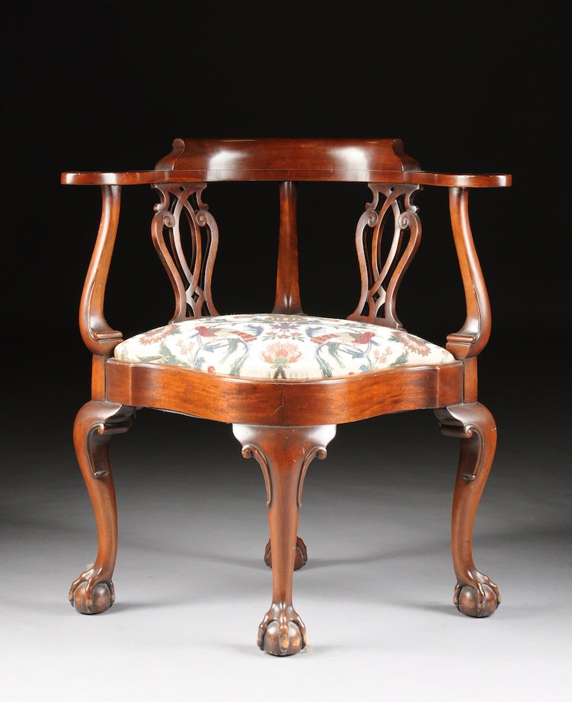 A CHIPPENDALE STYLE MAHOGANY CORNER CHAIR, 20TH CENTURY: A CHIPPENDALE STYLE MAHOGANY CORNER CHAIR, 20TH CENTURY, the curved back rest with outwardly scrolling arms, supported by two pierced carved back splats, over an upholstered seat with serpentine apron
