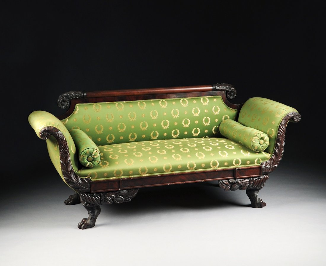 AN AMERICAN CLASSICAL CARVED MAHOGANY SOFA, NEW YORK, C: AN AMERICAN CLASSICAL CARVED MAHOGANY SOFA, NEW YORK, CIRCA 1825, the horizontal cylindrical crest rail ending in scrolling acanthus and flower head finials above a shaped rectangular padded back and 