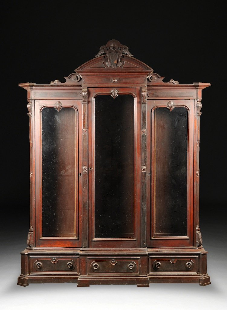 A LARGE AESTHETIC MOVEMENT WALNUT DISPLAY CABINET, CIRC: A LARGE AESTHETIC MOVEMENT WALNUT DISPLAY CABINET, CIRCA 1875, the arched cornice of scrolling shell and shield details above a breakfront glazed door with curling pendants opening to an adjustable sh