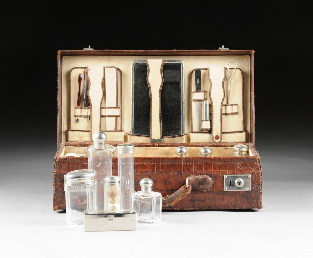 A GENTLEMEN'S TRAVELING TOILETRY SET, BY GUSTAV LOHSE,: A GENTLEMEN'S TRAVELING TOILETRY SET, BY GUSTAV LOHSE, BERLIN, EARLY 20TH CENTURY, within a rectangular alligator suitcase, opening to reveal a linen lined fitted interior with various silvered metal 