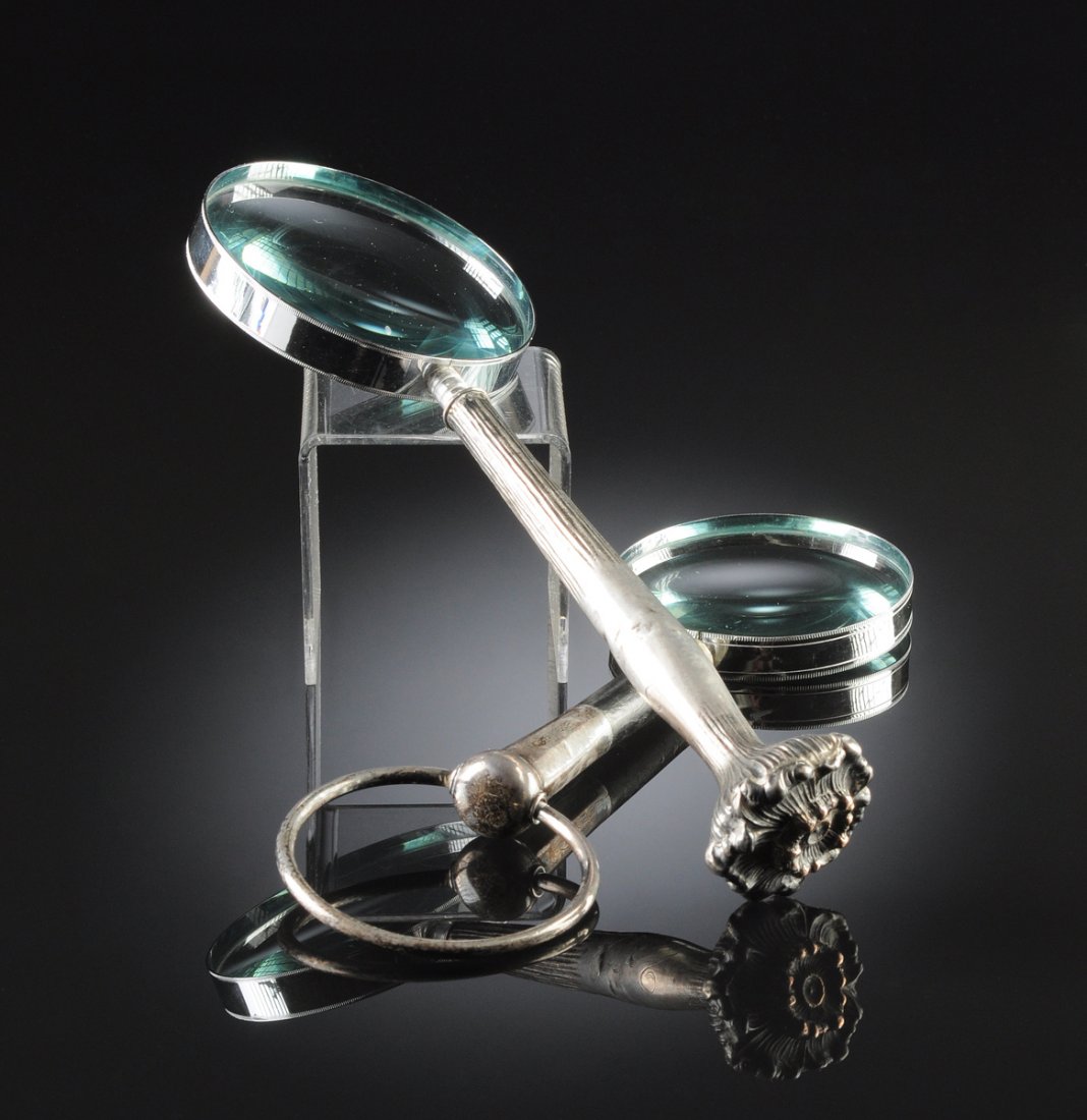 TWO VINTAGE SILVER PLATE MOUNTED DESK TOP MAGNIFYING: TWO VINTAGE SILVER PLATE MOUNTED DESK TOP MAGNIFYING GLASSES, 20TH CENTURY, one modeled as an elongated floral stem and centering engraved "MJB" initials, length: 11 3/4"; another with ebonized wood h