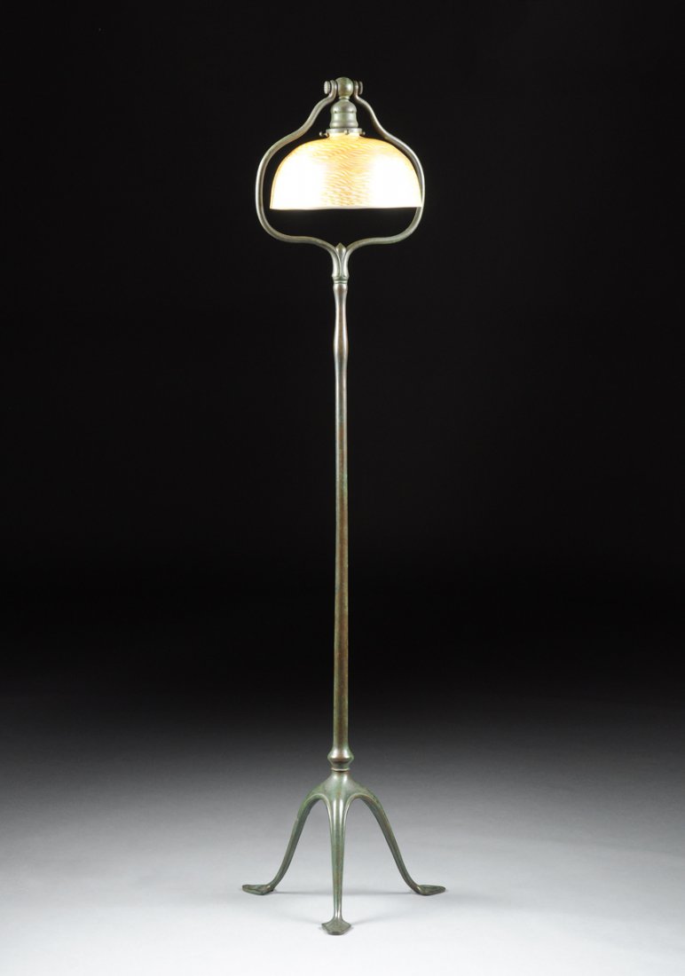 A LOUIS COMFORT TIFFANY GOLD AND YELLOW FAVRILE SHADE: A LOUIS COMFORT TIFFANY GOLD AND YELLOW FAVRILE SHADE ON A TIFFANY STUDIOS PATINATED BRONZE STAND, EARLY 20TH CENTURY, the domed shade centering sides of stylized wavy bands in iridescent gold and ton