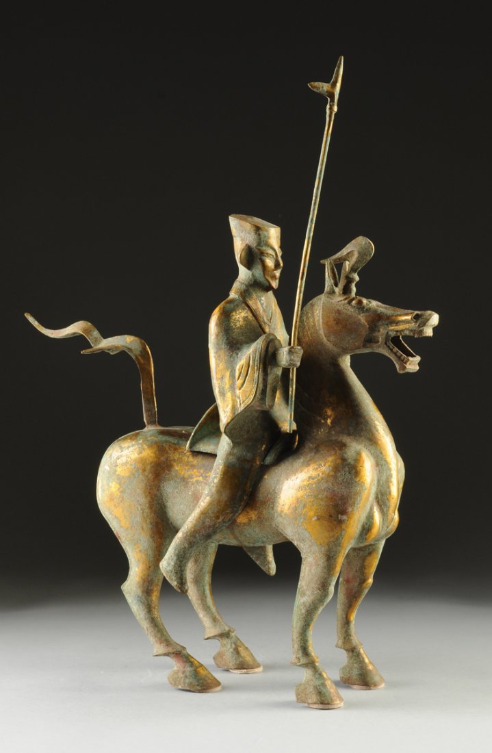 A CHINESE HAN DYNASTY STYLE PARCEL GILT BRONZE: A CHINESE HAN DYNASTY STYLE PARCEL GILT BRONZE EQUESTRIAN GROUP, LATE 20TH CENTURY, with oxidized verdigris areas throughout, and modeled with the horseman wearing a flat topped hat and flowing robes 