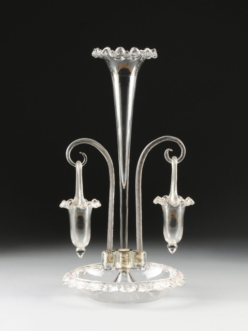 A VICTORIAN CLEAR GLASS EPERGNE, LATE 19TH/EARLY 20TH: A VICTORIAN CLEAR GLASS EPERGNE, LATE 19TH/EARLY 20TH CENTURY, the long flaring conical form vase with a ruffled rim flanked by finely twist-reeded scrolling arms suspending tapering circular baskets 