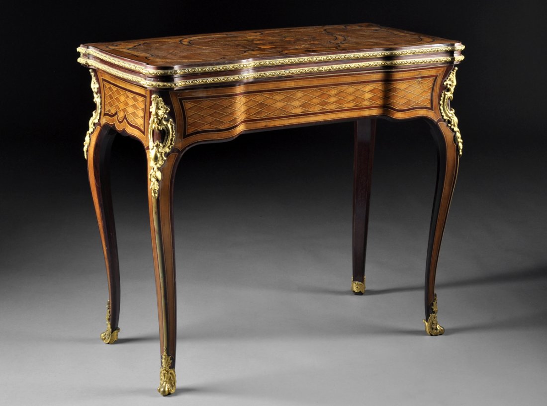 A LOUIS XV STYLE GILT BRONZE MOUNTED MAHOGANY AND: A LOUIS XV STYLE GILT BRONZE MOUNTED MAHOGANY AND VARIOUS WOODS INLAID MARQUETRY GAMES TABLE BY HENRY DASSON, FOURTH QUARTER 19TH CENTURY, the shaped rectangular folding top centering a stylized carto