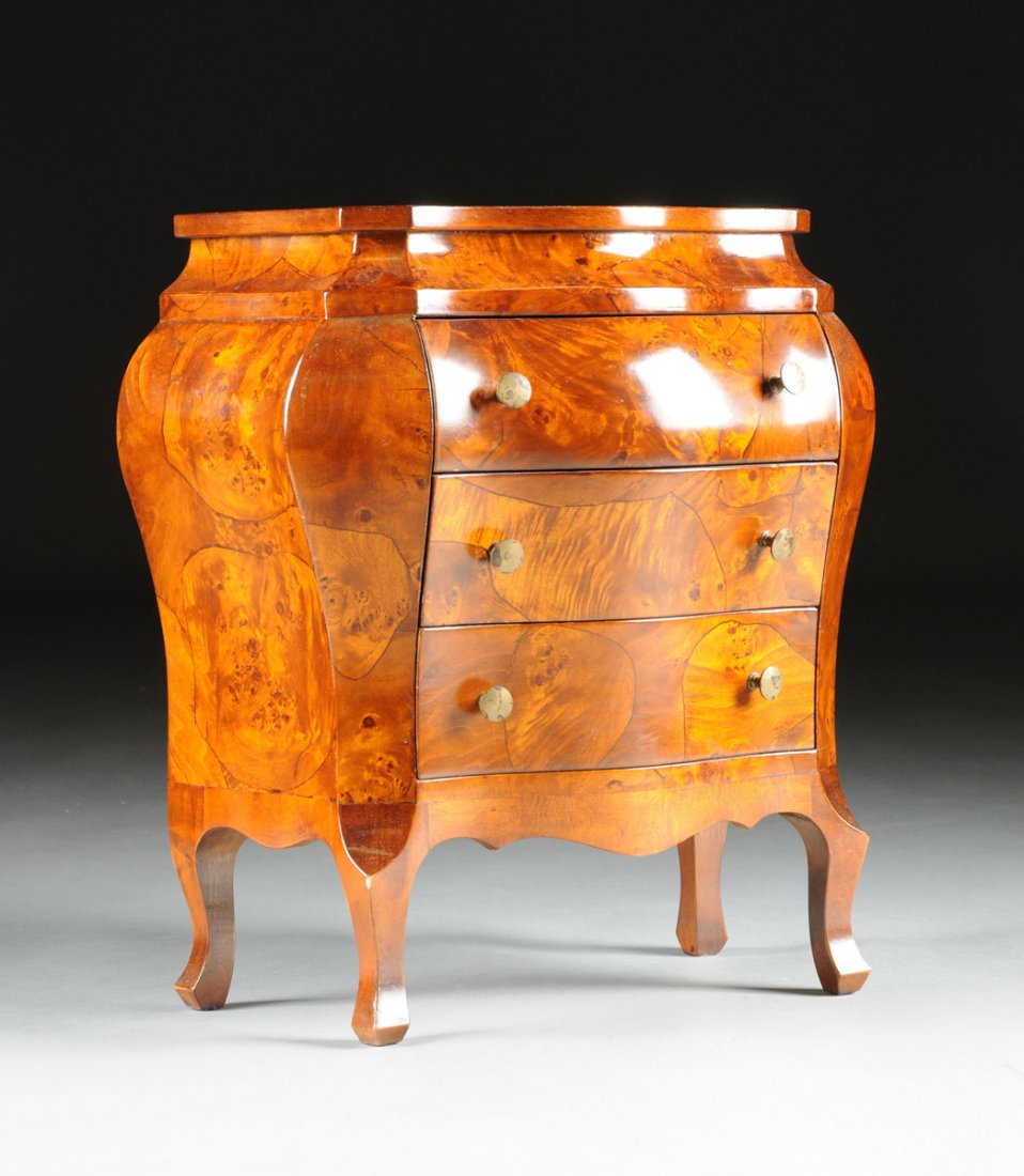 A DIMINUTIVE ITALIAN ROCOCO STYLE BOMBÉ WALNUT COMMODE,: A DIMINUTIVE ITALIAN ROCOCO STYLE BOMBÉ WALNUT COMMODE, 20TH CENTURY, the serpentine rectangular top above a conforming cavetto frieze and three tapering drawers centering circular bronze pulls, over