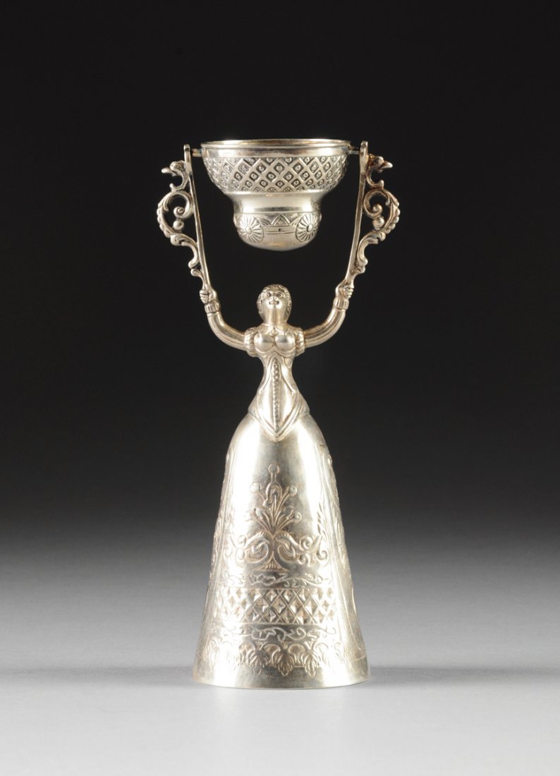 AN UNUSUAL AMERICAN STERLING SILVER FIGURAL MEASURING: AN UNUSUAL AMERICAN STERLING SILVER FIGURAL MEASURING CUP, NEW ORLEANS, POSSIBLY CIRCA 1880, modeled as a corseted maiden holding aloft two scrolling bracket supports flanking a swivel cup with trelli
