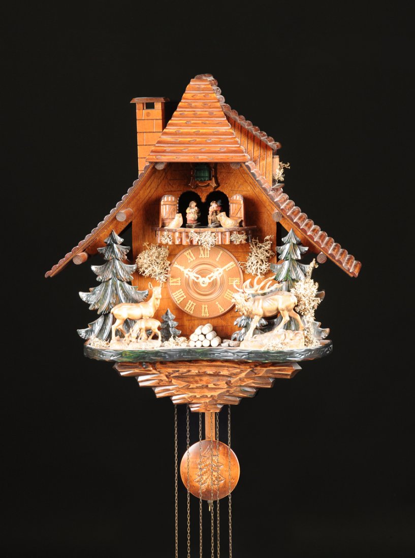 A LARGE GERMAN BLACK FOREST CARVED WOOD MECHANICAL: A LARGE GERMAN BLACK FOREST CARVED WOOD MECHANICAL HUNTING WALL CLOCK, 20TH CENTURY, the polychrome painted mountain chalet style case centering a circular dial having gothic style Roman hour chapters