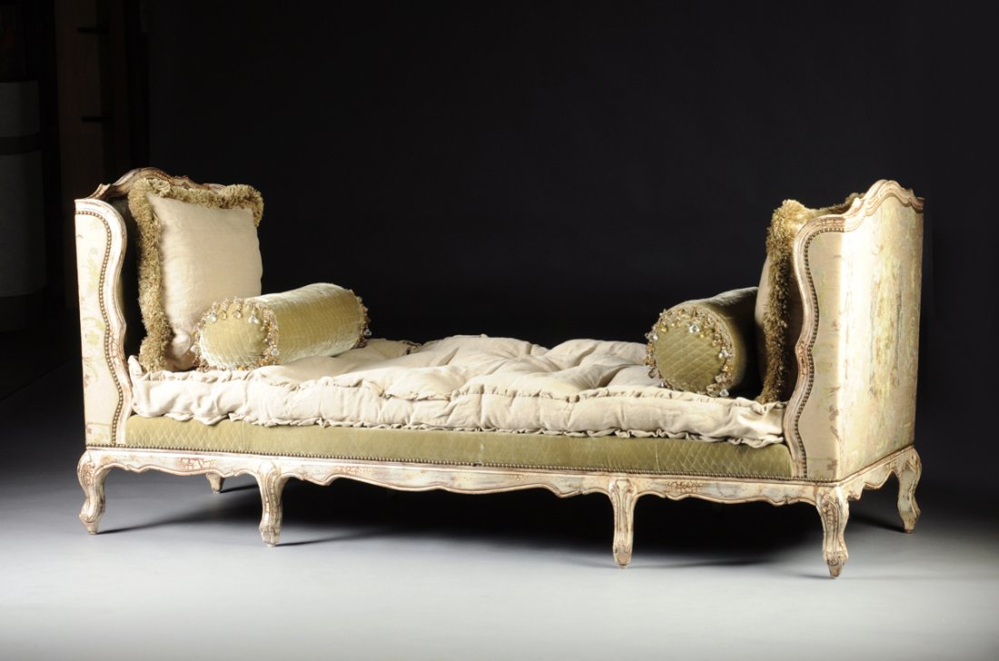 A LOUIS XV STYLE WHITE PAINTED AND UPHOLSTERED CARVED: A LOUIS XV STYLE WHITE PAINTED AND UPHOLSTERED CARVED WOOD DAYBED, MODERN, with serpentine rectangular à oreille padded and brass nail upholstered head and foot boards enclosing a similarly upholster