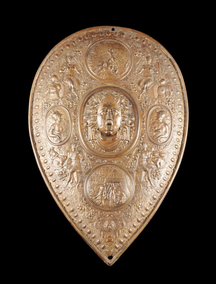 A CAST IRON SHIELD AFTER BENVENUTO CELLINI'S PARADE: A CAST IRON SHIELD AFTER BENVENUTO CELLINI'S PARADE SHIELD OF FRANCESCO I DE MEDICI, LAUSCHHAMMER, GERMANY, CIRCA 1880, the teardrop shape patinated cast iron shield with Medusa head at center flanked