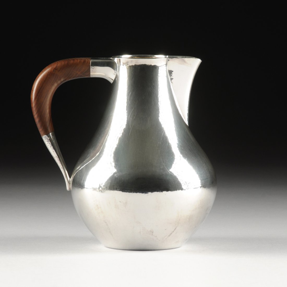 KARL GUSTAV HANSEN (Danish 1925-1994) A STERLING SILVER: KARL GUSTAV HANSEN (Danish 1925-1994) A STERLING SILVER AND ROSEWOOD WATER PITCHER, FOR HANS HANSEN, COPENHAGEN, DENMARK, 1958, of tapered baluster shape with figured rosewood D-shape handle, marks: "