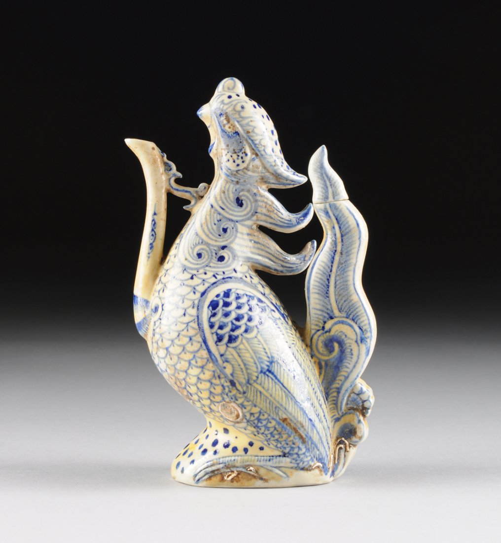 A VIETNAMESE/ANNAMESE BLUE AND WHITE PHOENIX FORM WINE: A VIETNAMESE/ANNAMESE BLUE AND WHITE PHOENIX FORM WINE EWER, POSSIBLY 15TH/16TH CENTURY, painted in underglaze blue details throughout and modeled as a stylized crested phoenix with its head slightly 