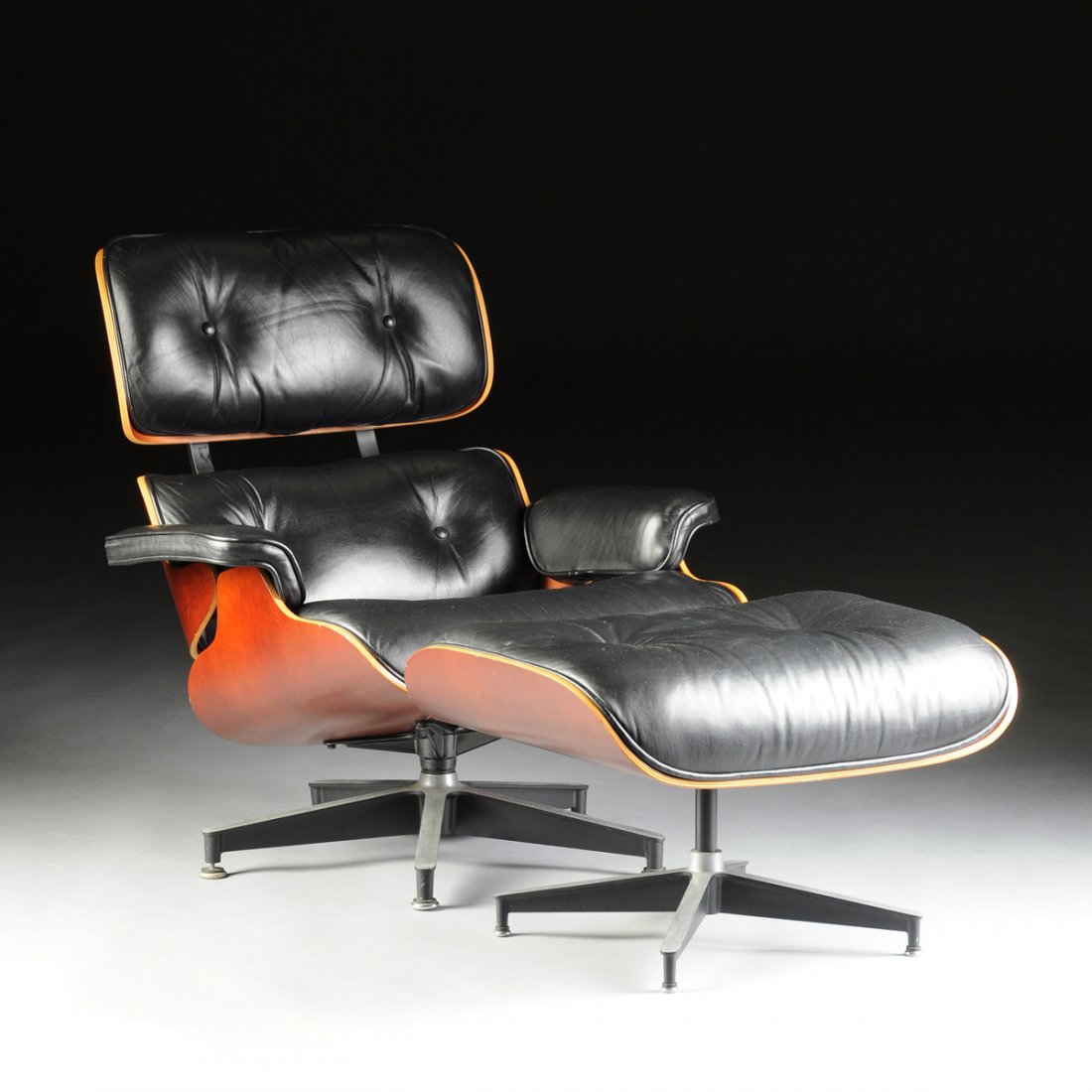 A CHARLES AND RAY EAMES(American 1907-1978/1912-1988): A CHARLES AND RAY EAMES(American 1907-1978/1912-1988) MOLDED WALNUT PLYWOOD, LEATHER, ENAMELED ALUMINUM AND RUBBER LOUNGE CHAIR MODEL 670 AND OTTOMAN MODEL 671, FOR HERMAN MILLER, INC., ZEELAND, MICHI