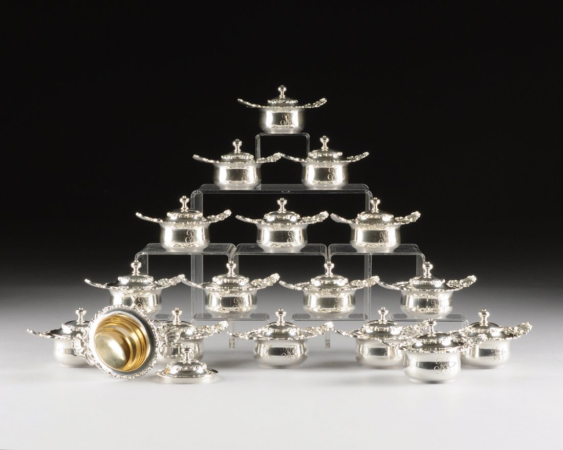 A SET OF SEVENTEEN AMERICAN STERLING AND GILT SILVER: A SET OF SEVENTEEN AMERICAN STERLING AND GILT SILVER COVERED CREAM POTS, BY MAUSER MFG. CO., NEW YORK, NEW YORK, CIRCA 1900, of kettle form with cast scroll and floral border, the shell shaped handles