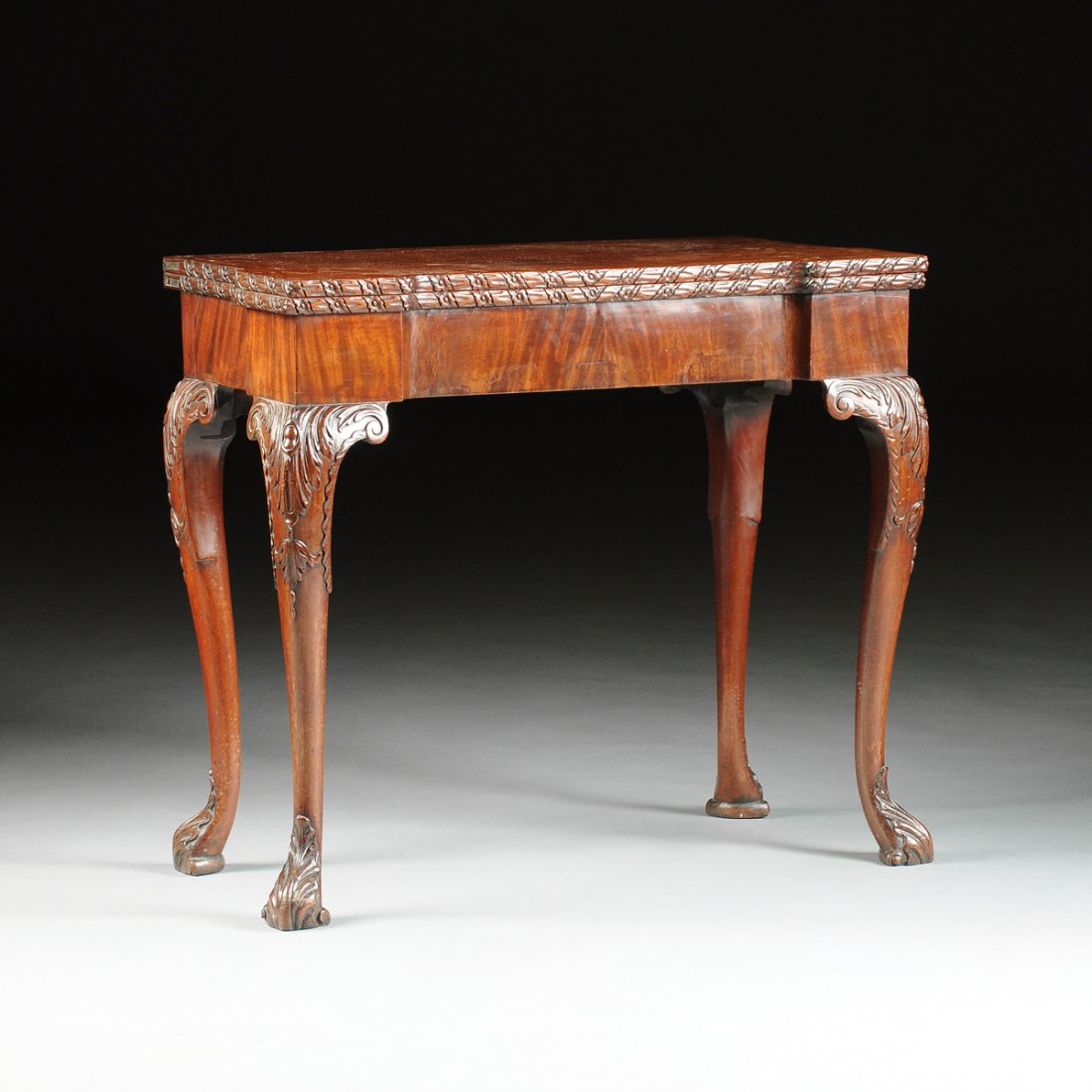 A GEORGE III MAHOGANY CONCERTINA ACTION GAMES OR CARD: A GEORGE III MAHOGANY CONCERTINA ACTION GAMES OR CARD TABLE, CIRCA 1760, in the manner of Thomas Chippendale (English 1718-1779), the hinged stepped square top with a continuous foliate trail carved e