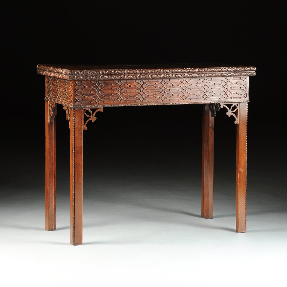 A GEORGE III MAHOGANY CARD TABLE, CIRCA 1765,: A GEORGE III MAHOGANY CARD TABLE, CIRCA 1765, in the manner of Thomas Chippendale (English 1718-1779), the hinged rectangular top with a continuous flower head carved edge and green baize lined playin