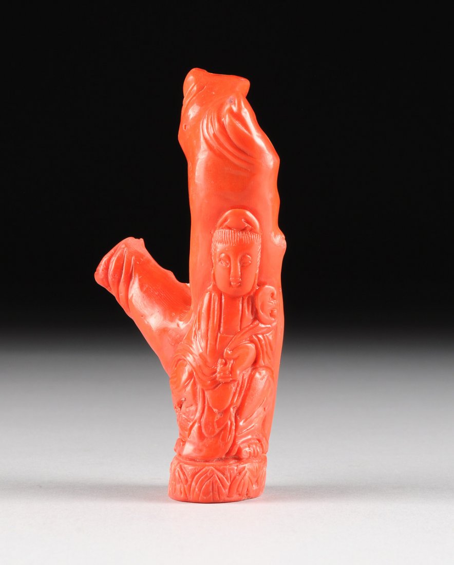 A CHINESE CARVED RED CORAL BRANCH, FOURTH QUARTER 20TH: A CHINESE CARVED RED CORAL BRANCH, FOURTH QUARTER 20TH CENTURY, the coral fragment retaining its natural form, the stalk carved in the likeness of Guanyin dressed in flowing robes, with hair pulled ba