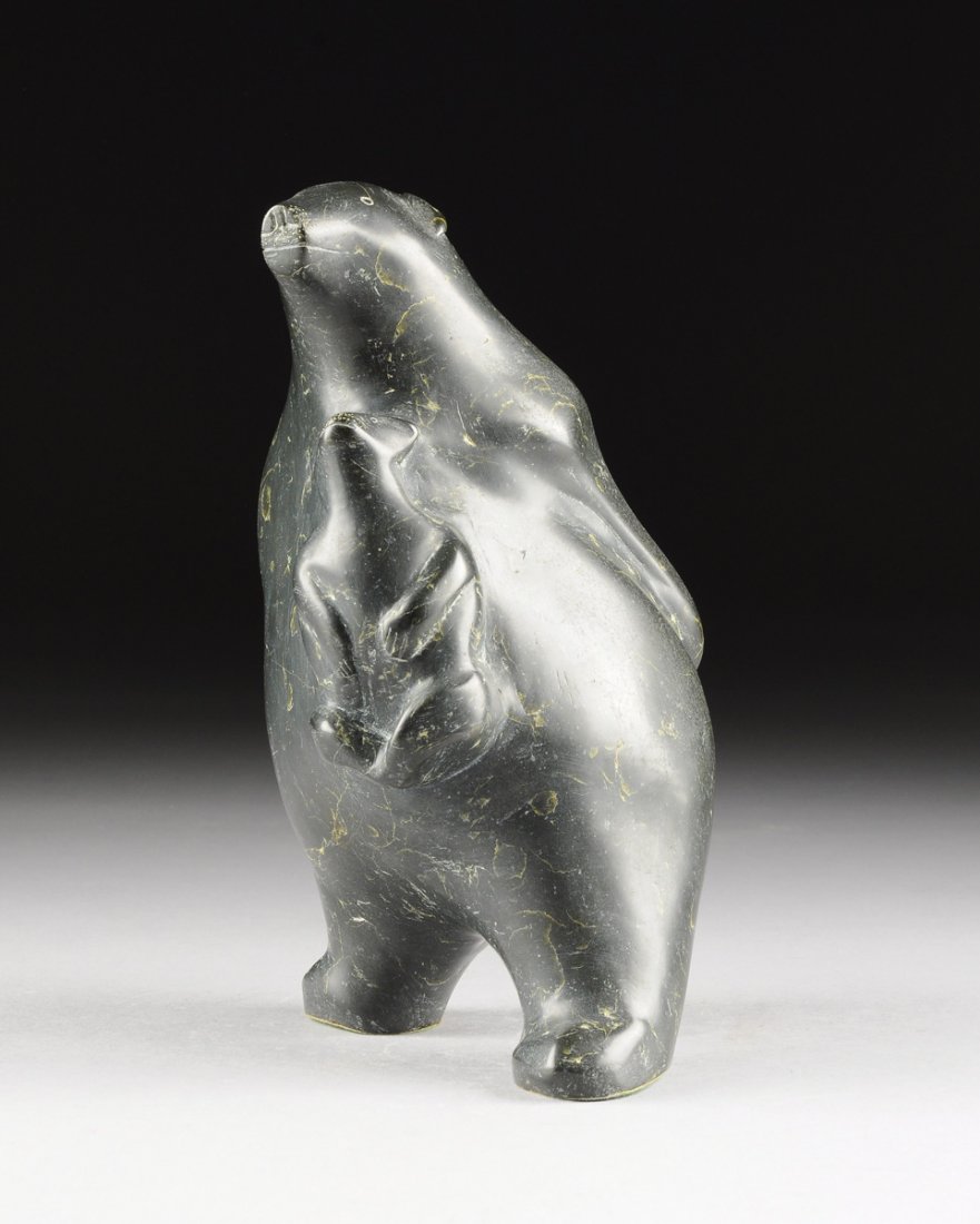 A CANADIAN INUIT SERPENTINE SCULPTURE, SECOND HALF 20TH: A CANADIAN INUIT SERPENTINE SCULPTURE, SECOND HALF 20TH CENTURY, in the form of an upright standing polar bear with arms crossed behind its back, attached near the bear's heart is a sitting cub lookin
