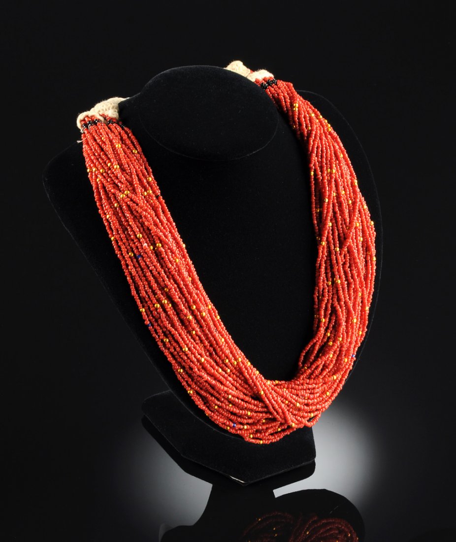 A JEWISH YEMENITE BEADED CORAL CHOKER LADY'S NECKLACE,: A JEWISH YEMENITE BEADED CORAL CHOKER LADY'S NECKLACE, 19TH CENTURY, a thick choker of multiple orange coral seed bead strands. The beginning and ending of the choker is woven, leading to a wrap strin